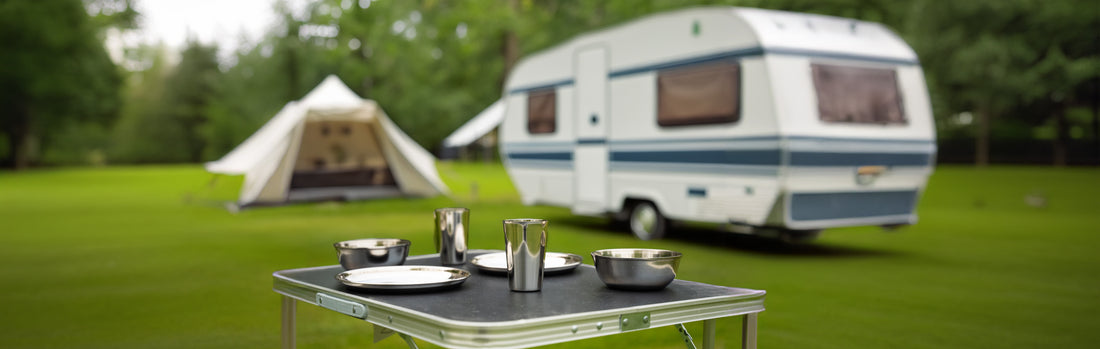 2 assiettes en acier inoxydable et 2 tasses et 2 bols sur une table dans un camping avec caravane et tente