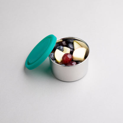 Stainless steel snack box filled with fruit with a green silicone lid