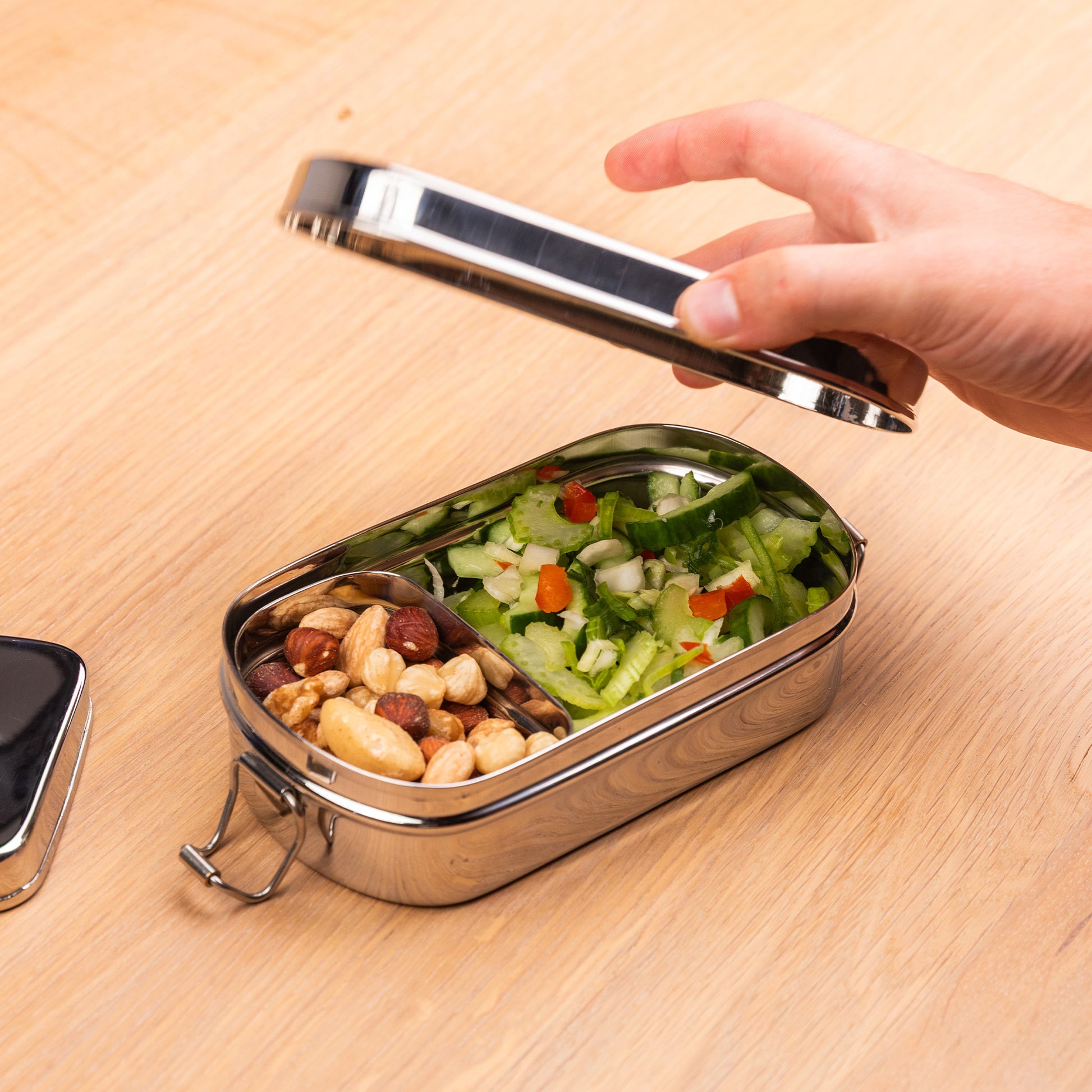 Stainless steel lunch box with snack box filled with nuts and salad