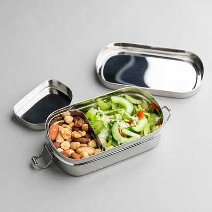 Stainless steel bread bin with compartments filled with nuts and salad, on a gray surface