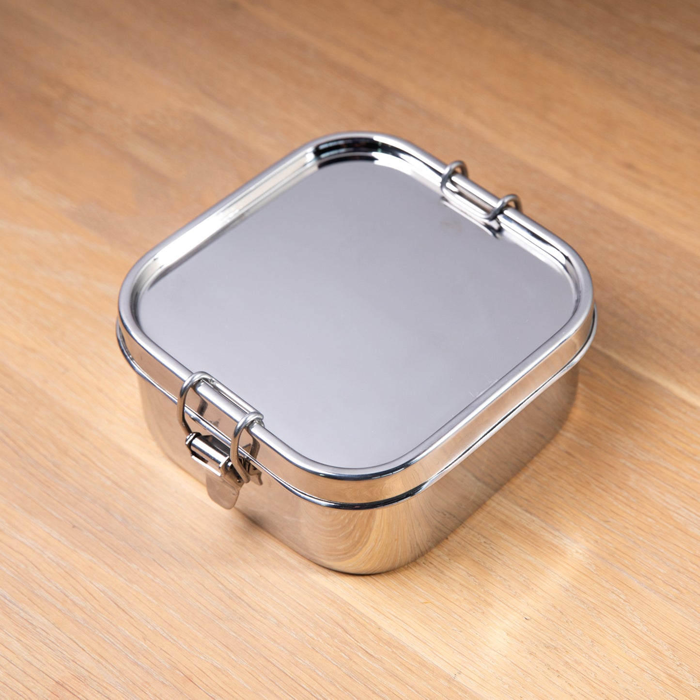 Stainless steel leak-proof lunch box on a wooden surface.