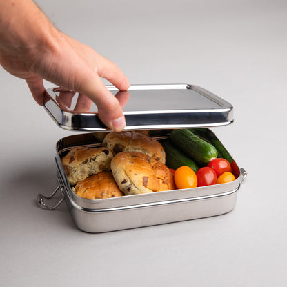 Stainless steel lunch box that is opened by one hand. richly filled with a healthy lunch