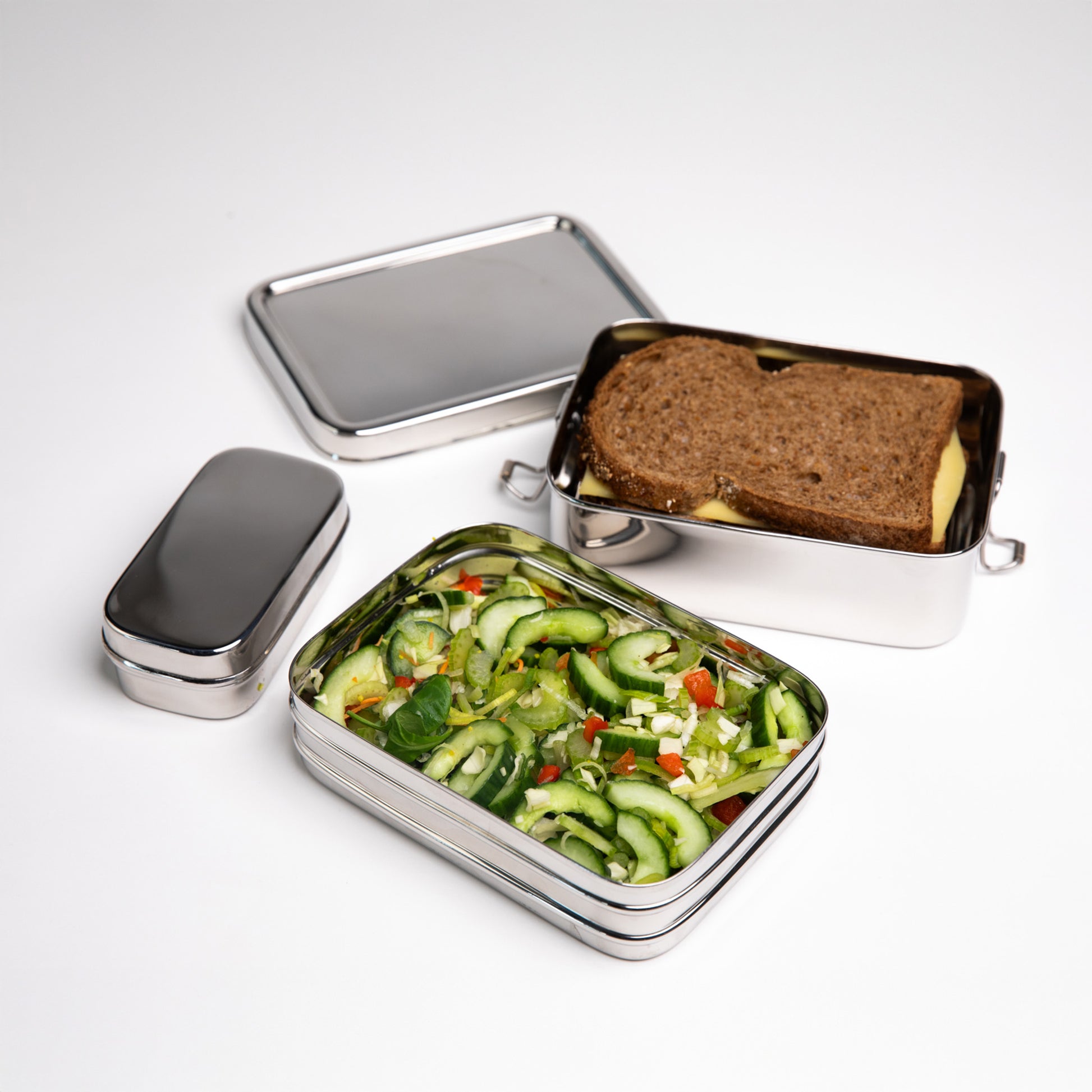 Stainless steel lunch box filled with a lettuce sandwich with a snack box
