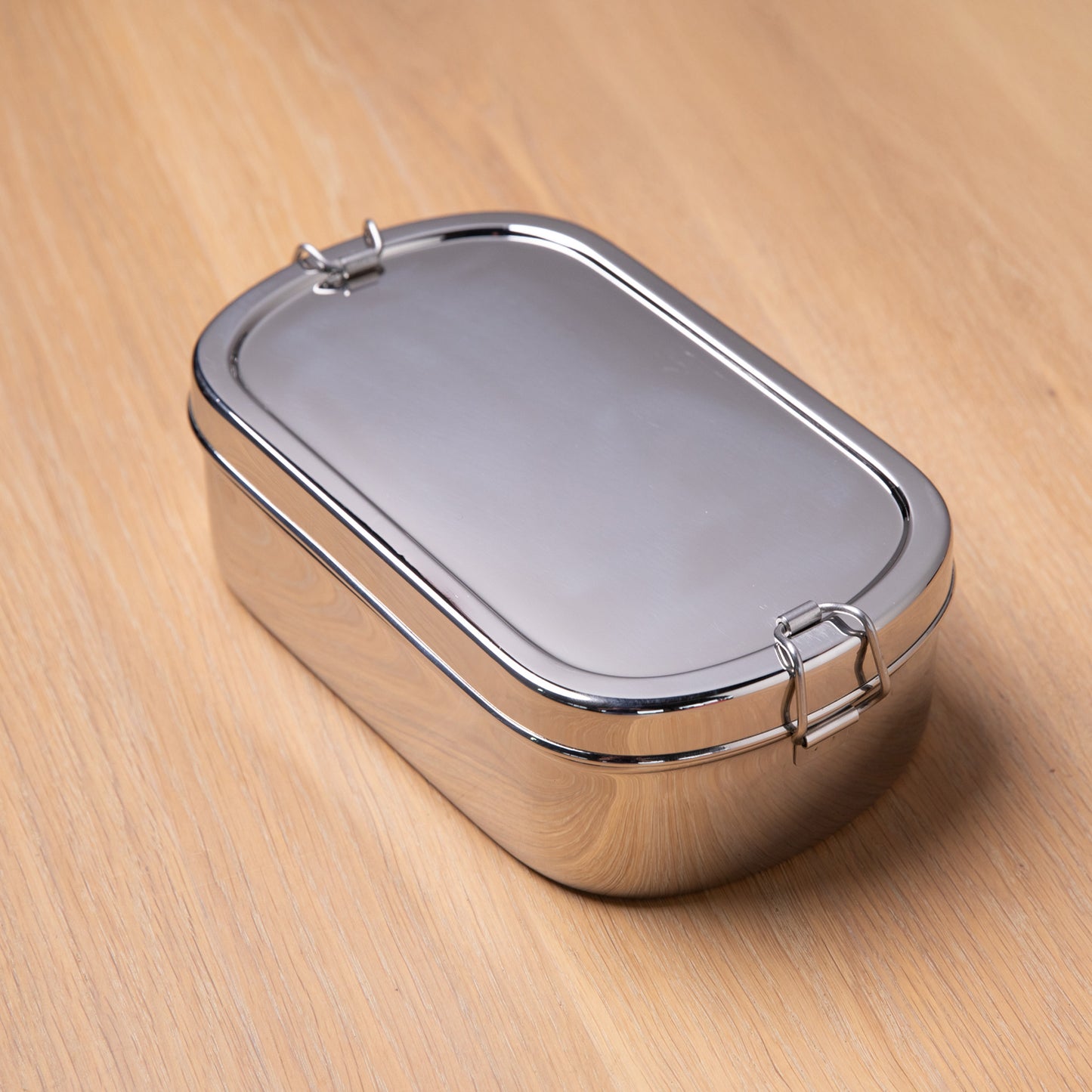Stainless steel lunch box for adults on a wooden surface