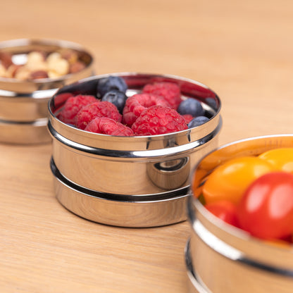 Stainless steel snack box filled with raspberries on a school table