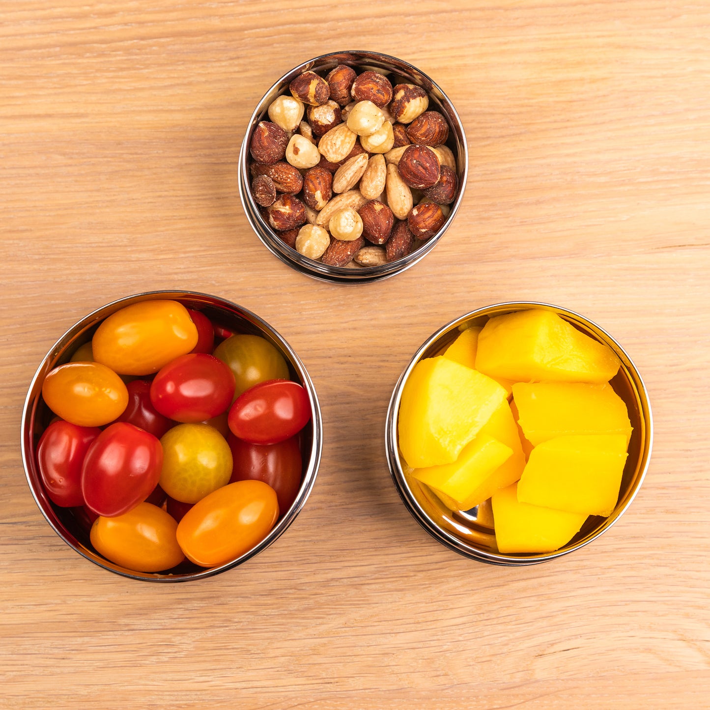 three stainless steel snack boxes filled with fruit and vegetables