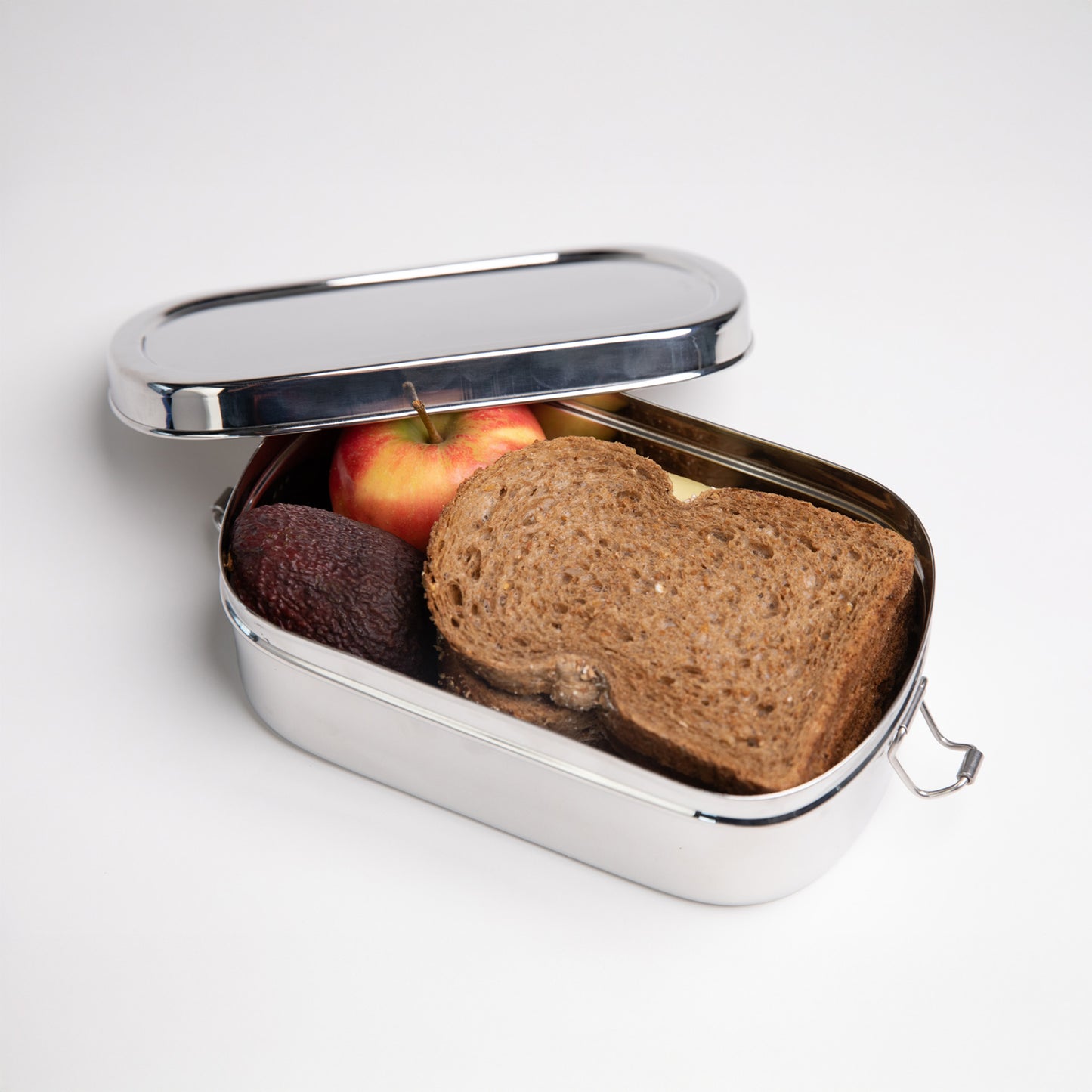 Stainless steel lunch box for adults open with an apple and an avocado inside
