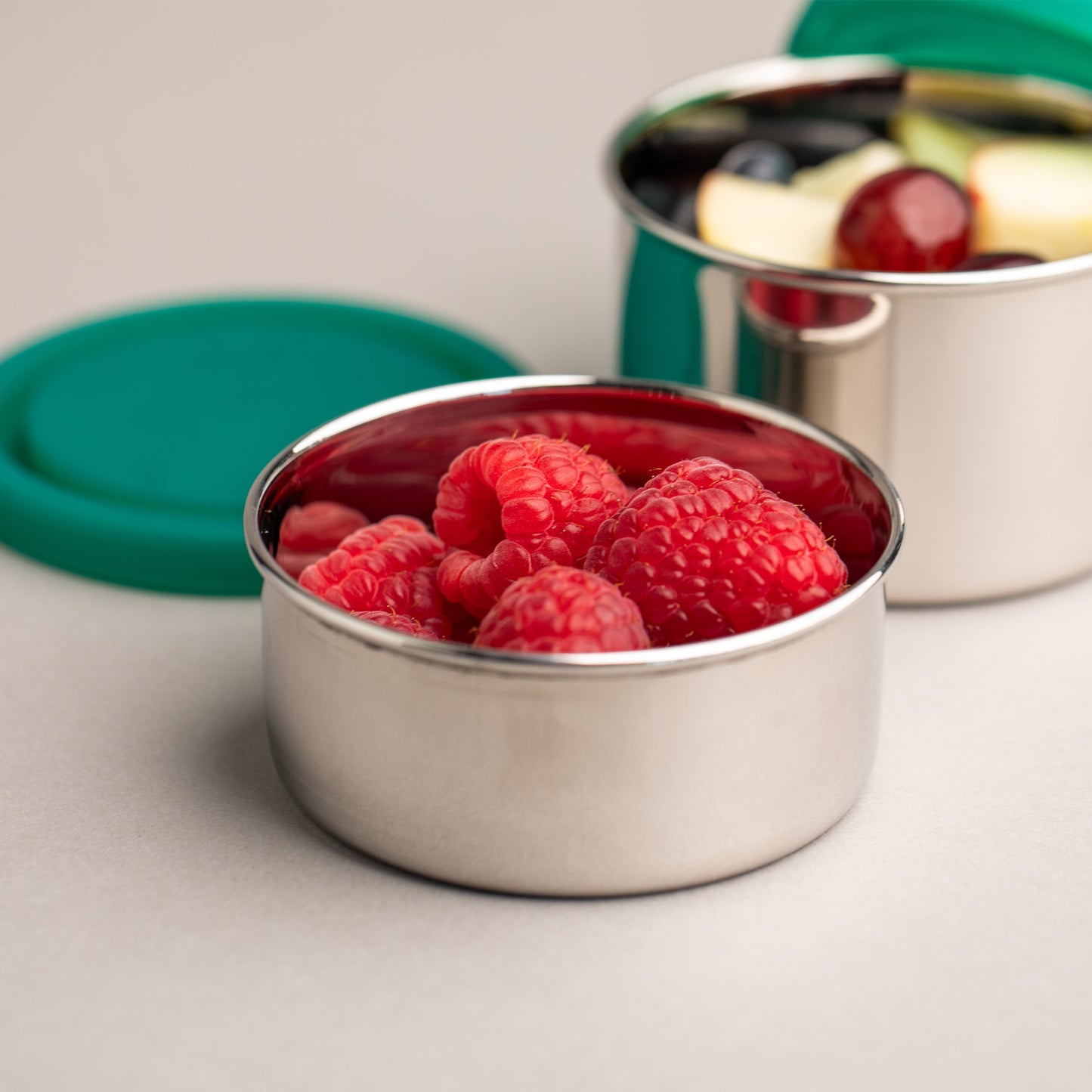 Stainless steel diamond container filled with raspberries and a silicone lid