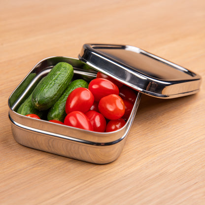 Stainless steel snack box filled with cucumber and tomato.