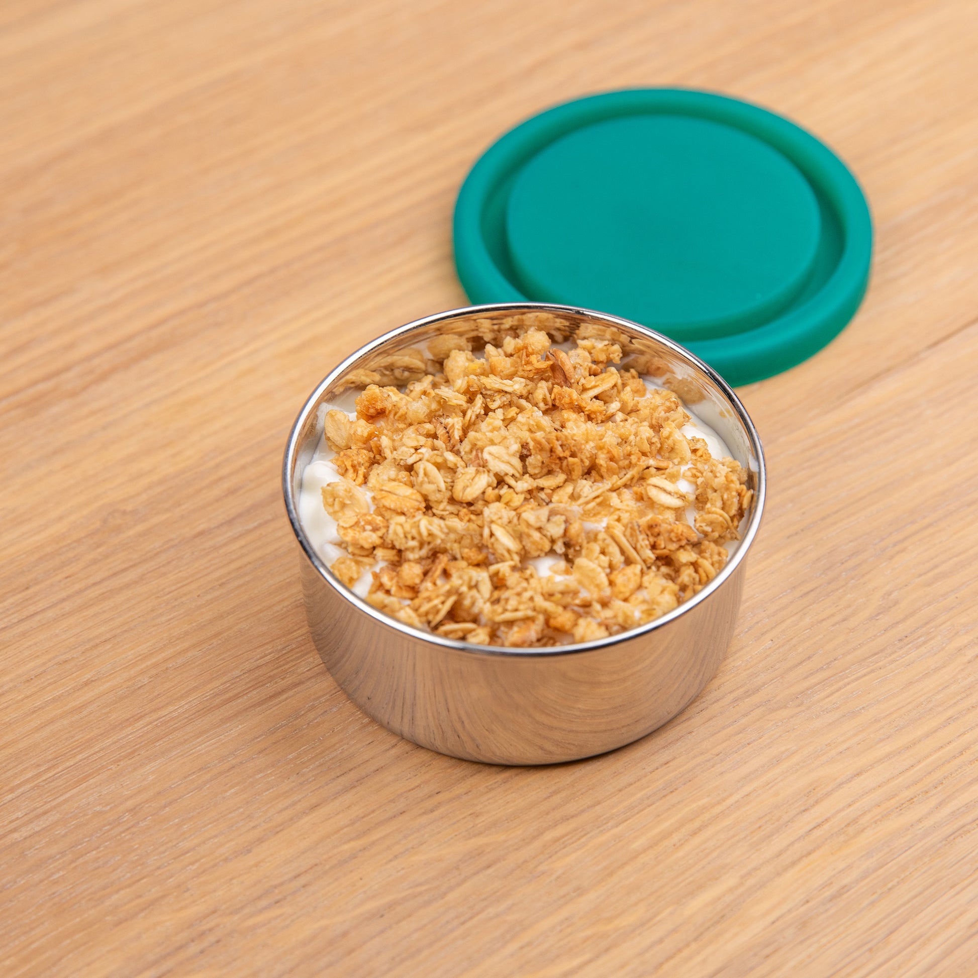 Stainless steel snack box filled with yogurt and musli.