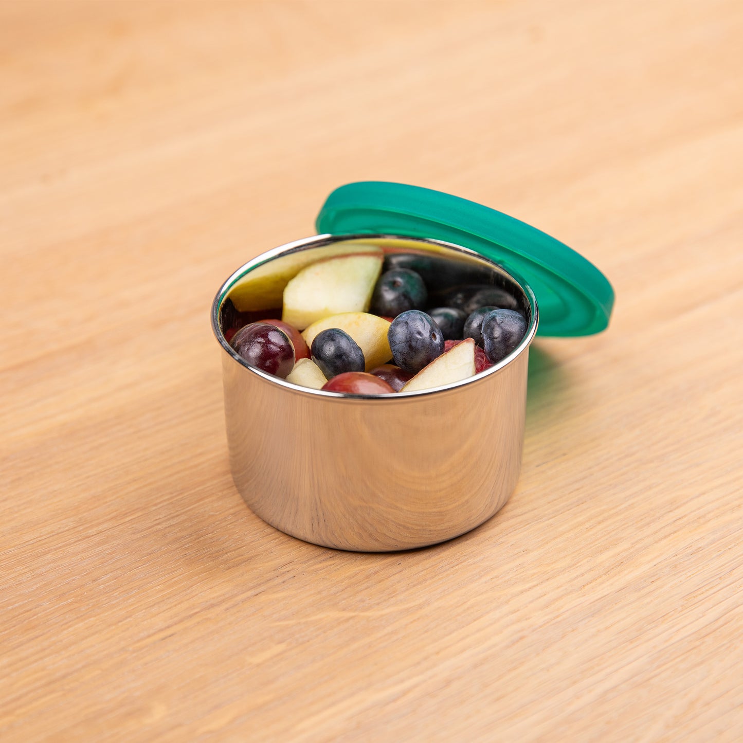 Leakproof stainless steel fruit container filled with apple and berries