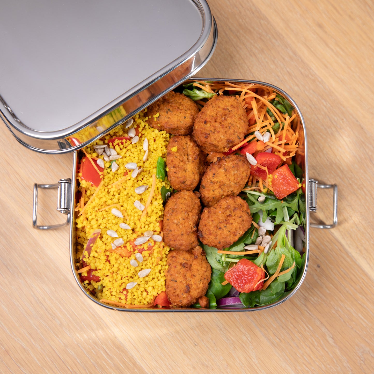 Leakproof stainless steel lunch box filled from above with a meal salad.
