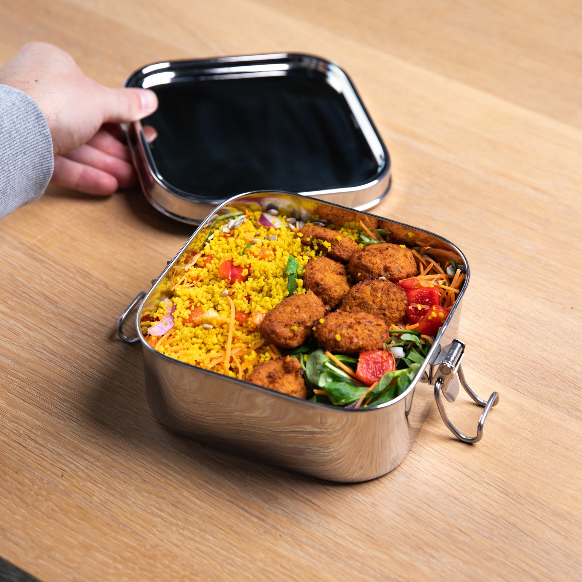 Stainless steel lunch box with lid filled with a falafel salad