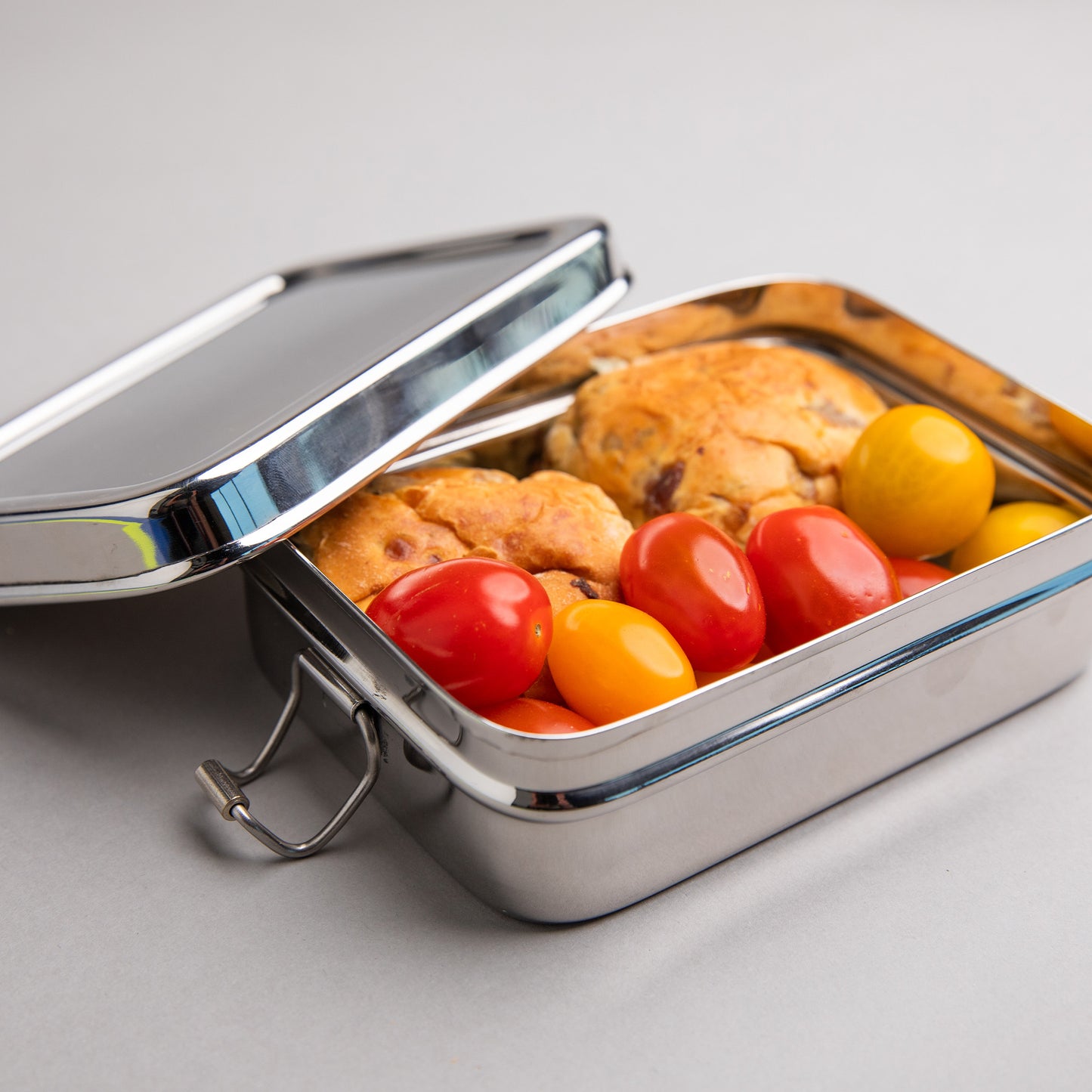 Stainless steel lunch box filled with tomatoes and currant buns