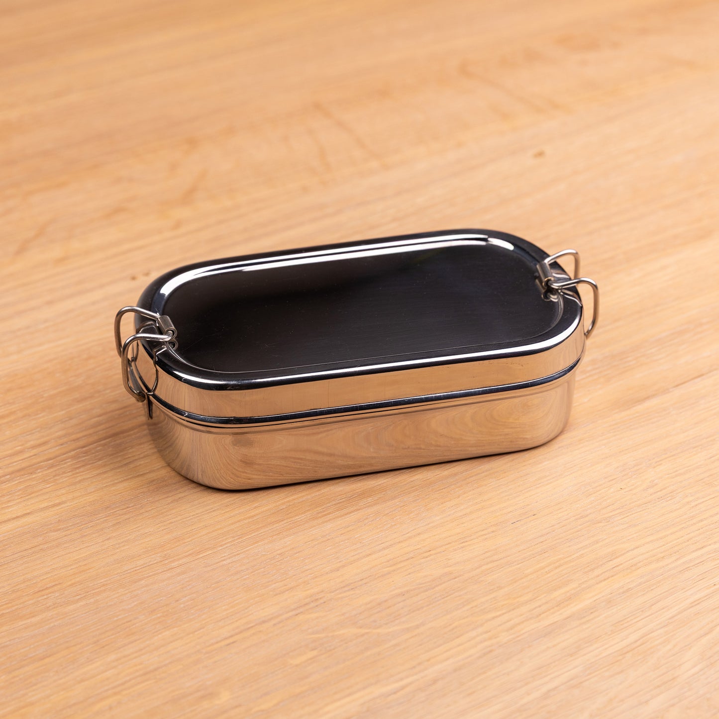 Stainless steel bento lunch box with compartments on a school table