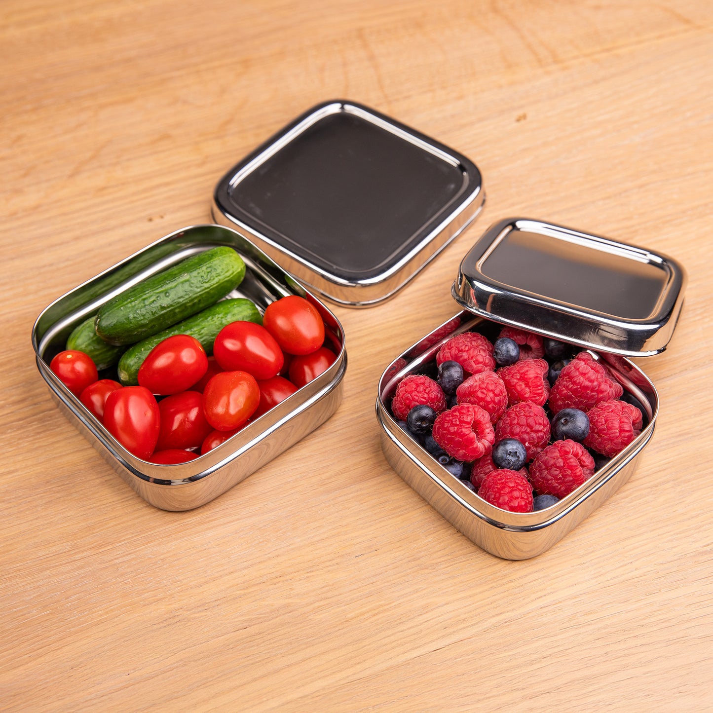 Stainless steel snack boxes on a school table filled with vegetables and fruit