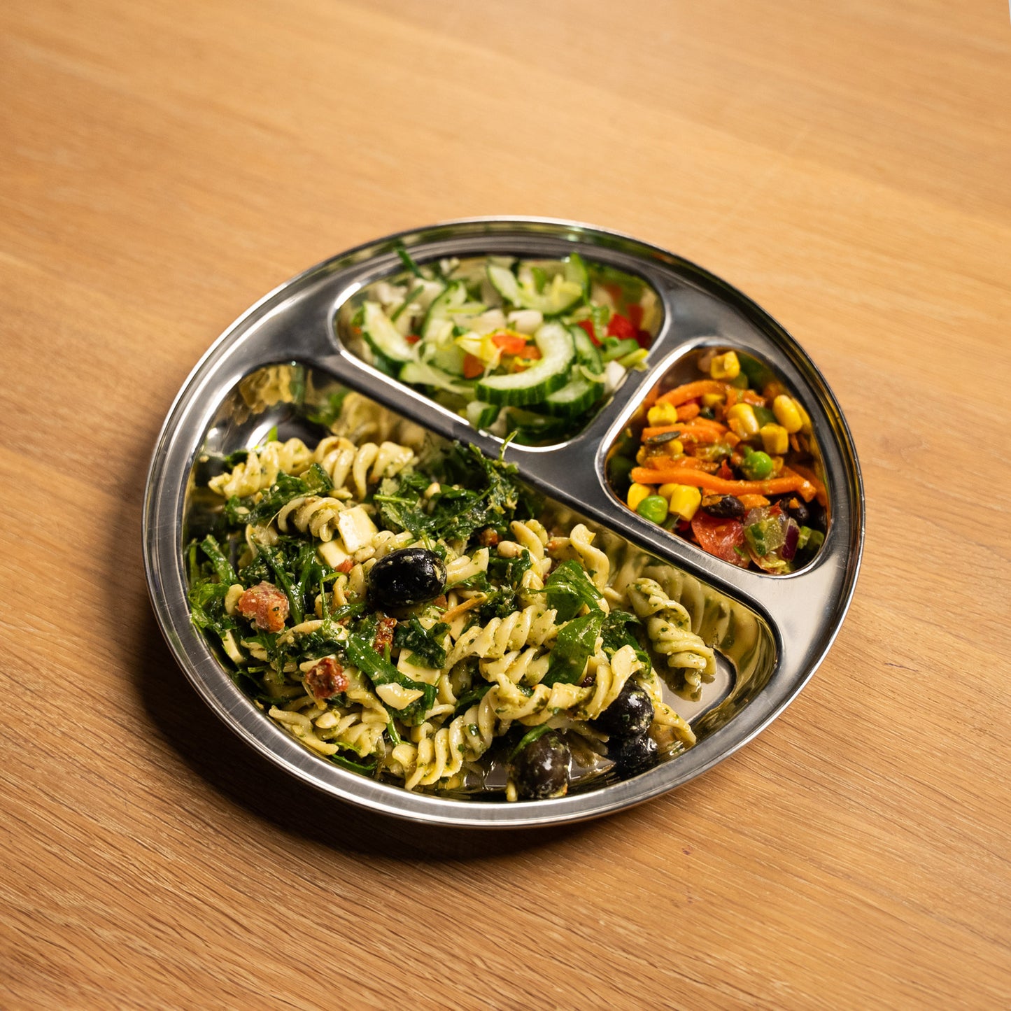 Stainless steel plate with compartments for children and adults. filled with pasta and salad