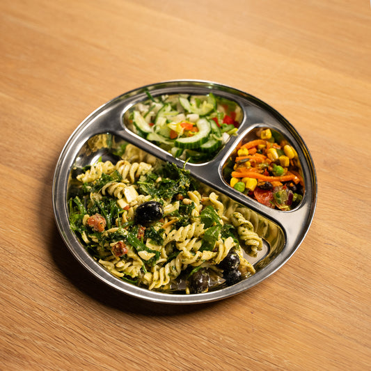 Stainless steel plate with compartments for children and adults. filled with pasta and salad