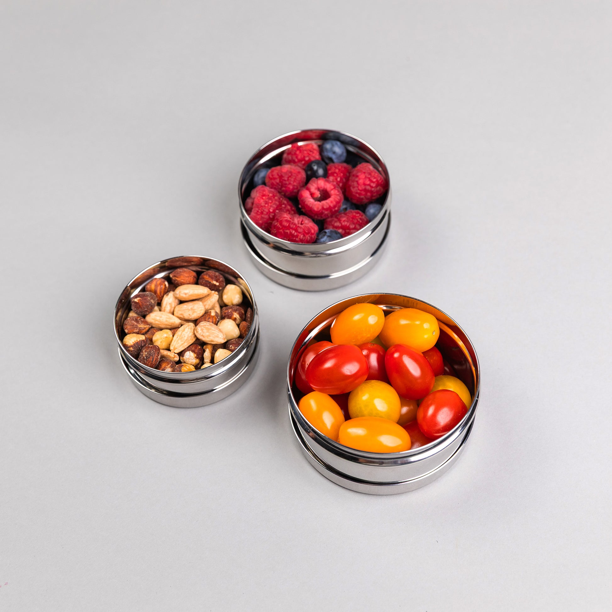 three stainless steel snack boxes on a gray background