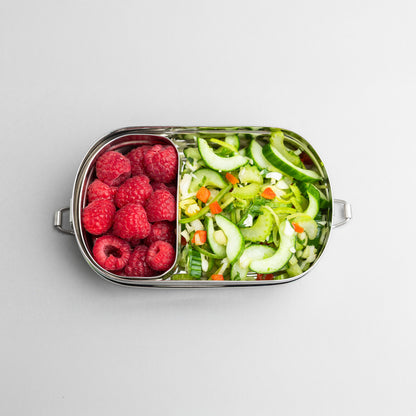 lunch box with compartments on top. filled with raspberry and salad